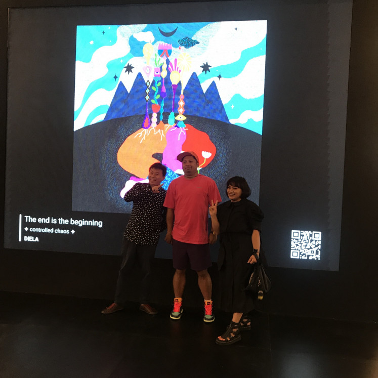 By threes: Tommy Chandra, Arya Mularama and Diela Maharanie stand in front of Dial’s NFT piece “The end is the beginning: controlled chaos” at the ArtMoments Jakarta exhibition on Nov. 4. (JP/Tunggul Wirajuda)