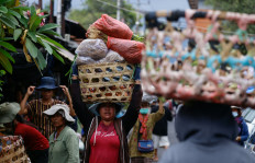 Women carry fruits and vegetables in baskets on their heads at a market in Denpasar, Bali, on Nov. 7, 2022.