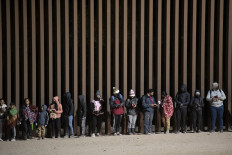 In this file photo taken on Dec. 26, 2022, asylum-seekers line up to be processed by US Customs and Border Patrol agents at a gap in the US-Mexico border fence near Somerton, Arizona.