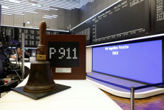 A traditional stock market bell is kept in front of a screen where Sports car maker Porsche is seen on the German DAX after a recent announcement on Deutsche Boerse's DAX indices in Frankfurt, Germany, December 19, 2022.