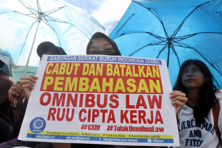 A woman from the Collective of Indonesian Trade Unions (GSBI) holds a poster calling for the revocation of the Omnibus Law on Job Creation on March 9, 2020, during a protest in front of the national legislature in Senayan, Jakarta.