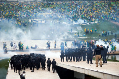 Supporters of Brazil’s former president Jair Bolsonaro demonstrate against President Luiz Inacio Lula da Silva while security forces fire tear gas, outside Brazil’s National Congress in Brasilia on Jan. 8, 2023.