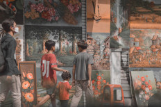 Art dealing: Children pass by Jelekong paintings showcased by local art dealers on the sidewalks of Jl. Braga. (Unsplash/ Aditya Enggar Perdana)