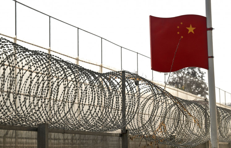 A border wall between China and Myanmar with barbed wire and a Chinese national flag is pictured on January 14, 2023, in Ruili, west Yunnan Province. 