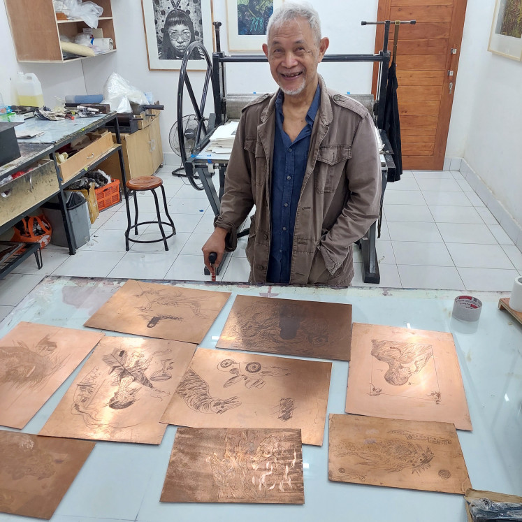Unexpected joy: Goenawan Mohamad poses with several etched copper plates at the DEVFTO Printmaking Institute at Sika Gallery in Ubud. (Courtesy of DEVFTO)