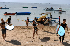 Surfers carry their surfboards as they return after a session at a beach in Sanur, Bali, on Jan. 18, 2023.

Sonny TUMBELAKA / AFP