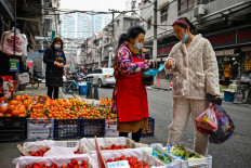 A customer (right) buys fruit at a local market in Wuhan, in China's central Hubei province, on January 23, 2023. 
