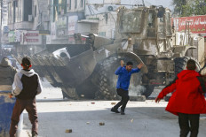 Palestinians hurl rocks at an Israeli army bulldozer, during confrontations in the occupied-West Bank city of Jenin, on Jan. 26. The Israeli raid on the West Bank’s Jenin refugee camp killed nine Palestinians including an elderly woman, Palestinian officials said, also accusing the army of using tear gas inside a hospital.
