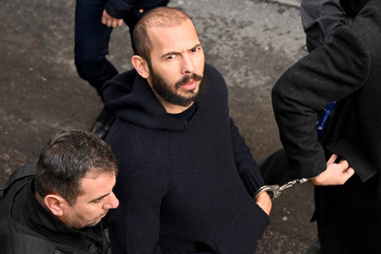 British-US influencer Andrew Tate arrives handcuffed and escorted by police at a courthouse in Bucharest on Feb. 1, 2023 to hear the court decision on his appeal against pre-trial detention for alleged human trafficking, rape and forming a criminal group. 