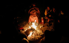 People warm up around a fire following an earthquake in Hatay, Turkey on February 7, 2023. 