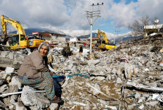 A woman sits amid rubble on Feb. 7, 2023, following an earthquake in Gaziantep, Turkey.