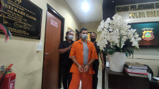 Antonio Strangio (in orange uniform) is escorted away by officers at the Bali Police headquarters in Denpasar on Feb. 8, 2023. The Italian-Australian national has been on the run from the police since 2016 for his alleged involvement in the illegal trade of 160 kilograms of marijuana.
