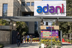 Employees walk past the Adani House corporate building at the institutional area in Gurugram on February 8, 2023. Shares in the flagship firm of troubled Indian conglomerate Adani rose almost 15 percent on February 7, clawing back some of its recent huge losses after saying it would repay more than $1 billion in loans.
