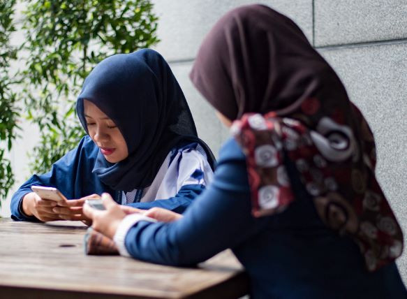 Women use their smartphones on Jan. 3, 2018, at a cafe in Jakarta.