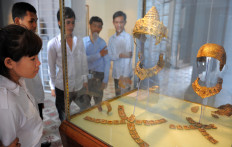Cambodian students look at the gold and rock crystal Royal Regalia of the Angkor period, 12th and 13th centuries, that is displayed at the National Museum in Phnom Penh on May 26, 2009. The stolen Royal Regalia was donated to the National Museum in January 4, 2008 by American Douglas Latchford.