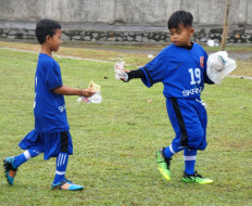 Tian (left) and Alif, players of Garuda Lions FC, pick up rubbish on the field as they have been taught to do at the club.