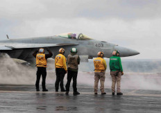rew members signal to a F/A-18E Super Hornet fighter jet preparing to take off for a routine flight on board the U.S. USS Nimitz aircraft carrier during a routine deployment to the South China Sea, Mid-Sea, on Jan. 27, 2023. R