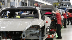 Employees of German car producer Porsche AG work on Porsche Taycan electric sports cars at the assembly line of the Porsche production site in Stuttgart, southwestern Germany, on September 26, 2022.