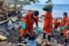 This handout photo taken on March 8, 2023 and released by the Philippine Coast Guard (PCG) shows coast guard personnel and volunteers collecting debris covered with oil during a clean-up along the coast in Pola, Oriental Mindoro Province, days after an oil spill from a sunken tanker.