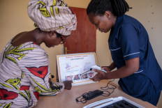 Rwandan midwife Christine Musabyeyezu (R) speaks to a patient about a thermal coagulator, a cost-effective alternative to cryotherapy, at Remera Health Centre in Kigali on March 7, 2023.