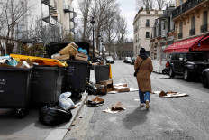 A person walks in a street where garbage cans are overflowing, as garbage has not been collected, in Paris, France March 10, 2023.