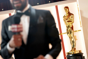 A member of the media speaks near a decorative Oscar statue on March 11, 2023, in Hollywood, a district of Los Angeles, California, as final preparations are made for the 95th Academy Awards.