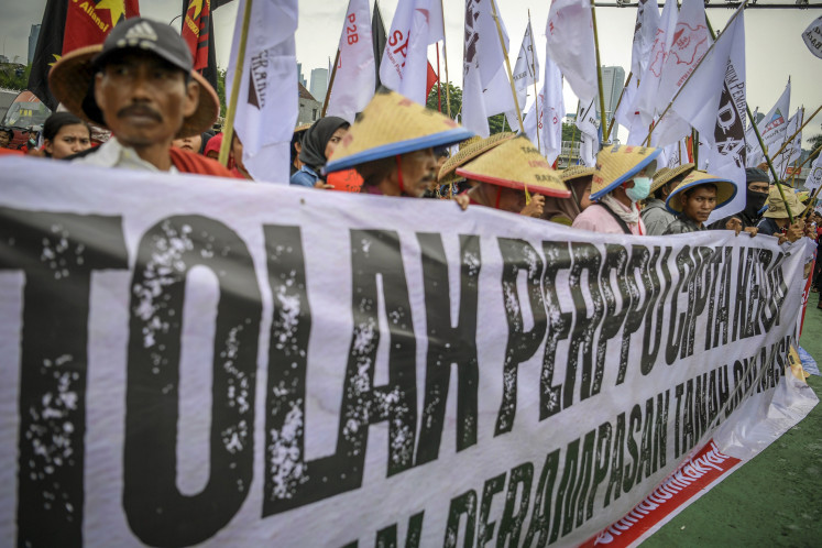 Workers from different labor unions, farmers and students display posters as they rally outside the House of Representatives in Senayan, Jakarta, on March 14, 2023, demanding the cancellation of the controversial Job Creation Law they said was not in their interest.