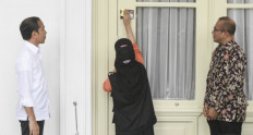 President Joko “Jokowi“ Widodo watches on March 14, 2023 as a worker from the General Elections Commission (KPU) places a registered voter sticker on a door of the Merdeka Palace, the official residence of Indonesia’s president.