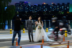 A couple pose for wedding photos as commuters drive past on a road in Seoul on October 28, 2021.