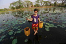 A girl collects drinking water at Dala river outside Yangon, Myanmar March 3, 2016.  