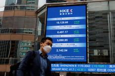 A man walks past a screen displaying the Hang Seng Index at Central district, in Hong Kong, China, on March 21, 2023.
