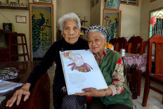 Vietnamese artist, Dang Ai Viet, poses with a woman she painted as a part of her project, “heroic mothers of Vietnam“, a term recognised by the Vietnam government for women who lost their husbands and sons to the Vietnam War, in Cao Lanh city, Dong Thap province, Vietnam, March 8, 2023. 