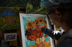 This picture taken on February 19, 2023 shows artist Deng Fei painting a replica of Vincent van Gogh's “Sunflowers“ in an alley at Dafen village, in Shenzhen, in China's southern Guangdong province. Painters in Dafen once known for churning out fakes are now selling original works worth thousands of dollars, adapting their styles and making the most of a booming domestic art market.
