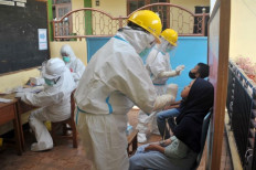 Mandatory testing: Medical workers conduct swab tests for COVID-19  on Jan. 27, 2022, at a boarding school in Bandung. 