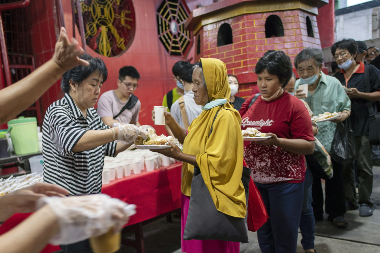 Residents take tajil food distributed for breaking the fast by a committee from the Dharma Bhakti Temple in Petak Sembilan, Glodok, West Jakarta, on March 28, 2023. The Dharma Bhakti Temple distributes hundreds of tajil packages to Muslims during Ramadan. The charity is held annually as an expression of tolerance among religious followers.