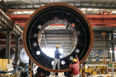 Employees work on a wind turbine tower drum at a factory in Lianyungang, in China's eastern Jiangsu province, on April 18, 2023.

