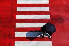 People hold an umbrella while crossing the street as temperatures hit a record 45.4 degrees Celsius in Bangkok, Thailand on April 22, 2023.