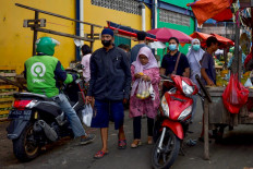 People walk past street vendors at a traditional market in Jakarta on April 28, 2023. The number of COVID-19 cases in the country experienced an uptick after Idul Fitri holiday. 