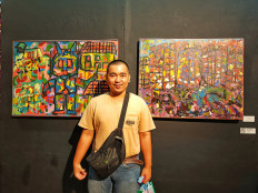 Proud: Anugrah Fadly stands between his paintings 'Pendidikan Robot' (left) and 'Abstraksi Gempa Turki' (JP/Sylviana Hamdani)
