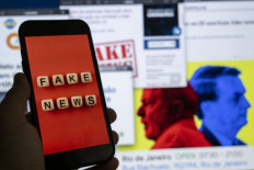This illustration, made in August 2022, shows a smart phone screen displaying the phrase “Fake News“ in front of a desktop screen showing several news and research reports about fake news and disinformation related to the Brazilian presidential election. Brazil’s National Consumer Protection Bureau has ordered Google to label as “advertising” messages on its site warning that a legislation to tackle disinformation could “make your internet worse” and “increase confusion about what is true or false in Brazil”.