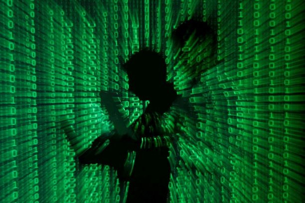 Protection first: A binary code is projected on a man holding a laptop computer. Laptops, PCs and printers are becoming more prone to cyberattacks.