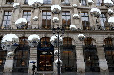 A woman under an umbrella walks past the luxury retailer Louis Vuitton store at Place Vendome in Paris on March 2, 2023. 