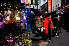 Visitors walk past vendor stalls and shops in Namdaemun Market in Seoul on March 13, 2023.

