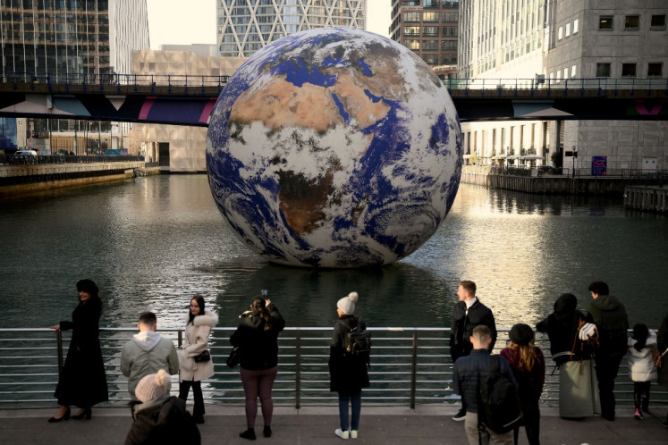 People take pictures with “Gaia“, British artist Luke Jerram's huge floating Earth installation, in Canary Wharf in London on Jan. 20, 2023.
