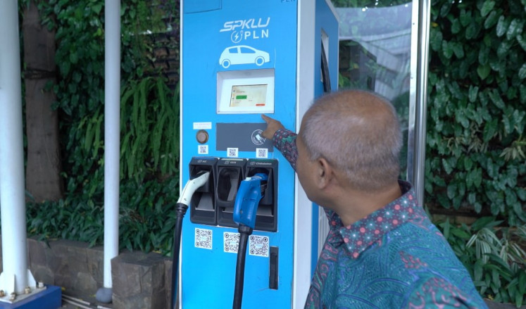 Arwani Hidayat tracks the counter on April 12, 2023, as he charges his electric vehicle at a charging station in Central Jakarta. He plans his journeys carefully to account for charging
time, especially for long trips.