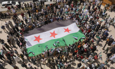 Demonstrators hold the Syrian opposition flag as they gather during a protest against Arab normalization with Syria's President Bashar al-Assad and the Arab League's reintegration of Syria, in the rebel-held city of Azaz, Syria May 19, 2023. 