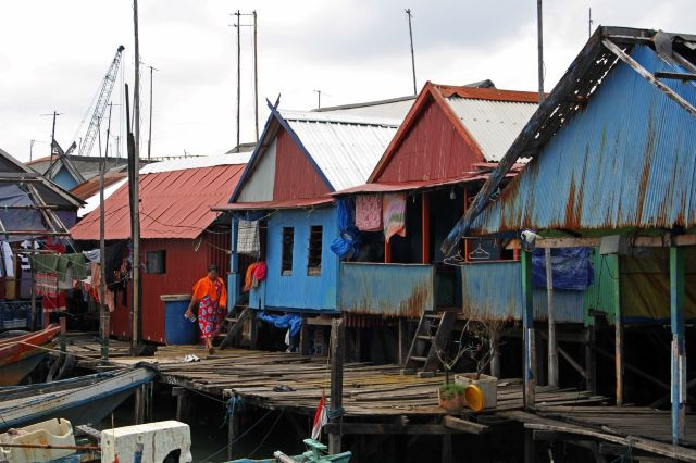 A woman walks past stilt houses on May 15, 2023 in a densely populated area in Makassar, the provincial capital of South Sulawesi. The government aims to eliminate extreme poverty by 2024.