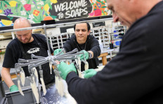 Workers dip orchid leaves into soap and hang them to dry in the soaps department at Lush cosmetic company in Poole, England, on May 9, 2023. Known for its colourful shampoo bars and fruity bath bombs, British cosmetics brand Lush has opened the doors of its new Green Hub as part of efforts to “close the loop“ on packaging and water waste. Here at the company's home base in Poole, southern England, its signature black pots are granulated into plastic pellets before being remoulded, while dirty water from manufacturing is clarified by a dissolved air floatation unit.
