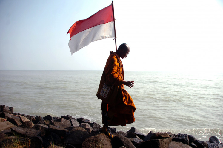 A Buddhist monk stands on May 24, 2023, among the rocky shore at Purwahamba Indah Beach in Tegal, Central Java, during the visit of 32 monks from Nakhon Si Thammarat in Thailand to take part in the Waisak rituals on June 4 at Borobudur Temple in Magelang.