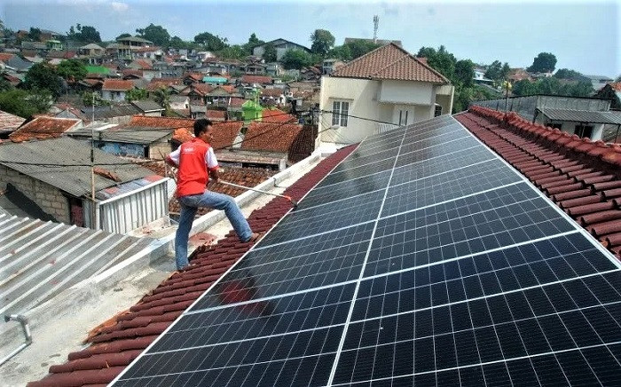 A maintenance worker cleans solar panels on May 14, 2022 on the rooftop of a frozen food factory in Bogor, West Java.